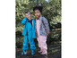 Deux enfants en vêtements de pluie, l'un avec un pantalon bleu, l'autre avec un motif floral, près d'un ruisseau.