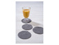 Un verre de jus d'orange sur une table avec quatre dessous de verre tricotés