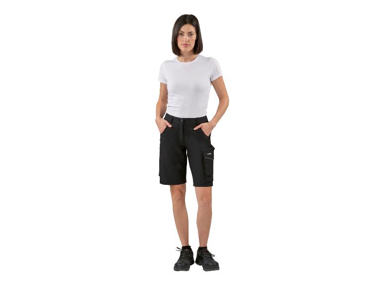Une femme portant un pantalon de travail noir avec des poches et des chaussures de sécurité noires.