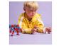 Un garçon joue avec un robot rouge et une figurine blanche sur un fond violet.