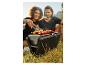 Couple préparant des brochettes et du maïs sur un barbecue portable.