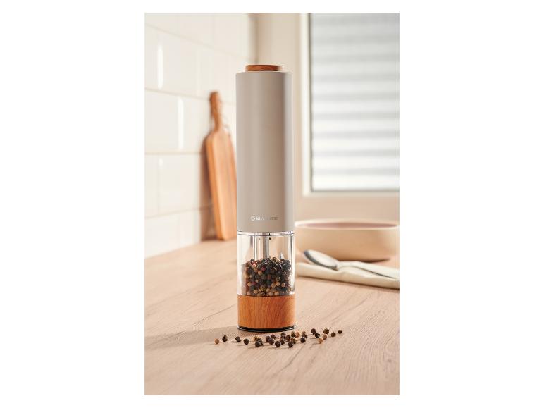 Moulins à sel et poivre électriques avec base en bois et grains de poivre sur un comptoir de cuisine.
