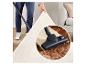 Homme passant l'aspirateur sur un tapis blanc, avec un gros plan de la tête d'aspirateur aspirant la saleté.