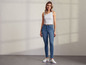 Une femme porte un débardeur blanc et un jean skinny.