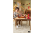 Un enfant joue avec un set de pizza jouet, des boissons et une bouteille de ketchup sur une table en bois.