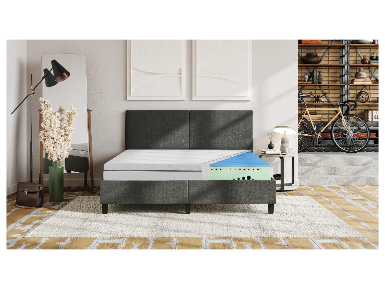 Un lit gris avec un matelas en mousse à plusieurs couches.