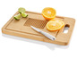 Une planche à découper en bois avec un couteau, des oranges et des citrons verts.