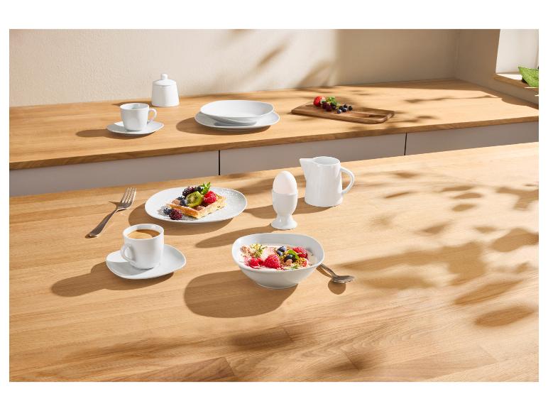 Petit-déjeuner avec gaufre aux fruits, yaourt, café et œuf sur une table en bois.