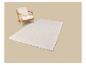 Tapis crème à motif géométrique et fauteuil en bois.