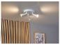 Un luminaire blanc au plafond avec trois lumières dirigées vers un mur en bois.