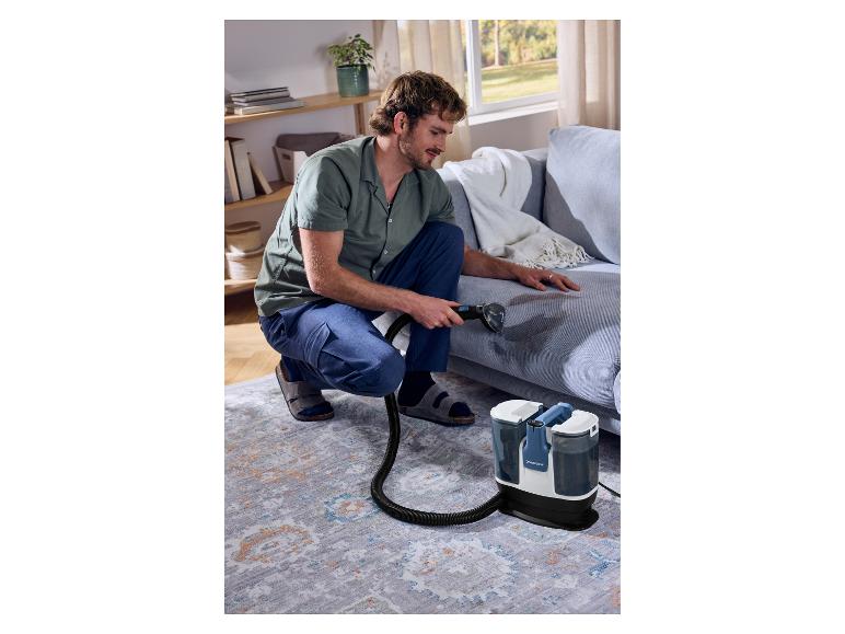 Un homme nettoie le canapé avec le nettoyeur de tapis et moquettes SILVERCREST®.