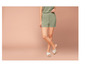 Femme portant un short vert et des sandales blanches.