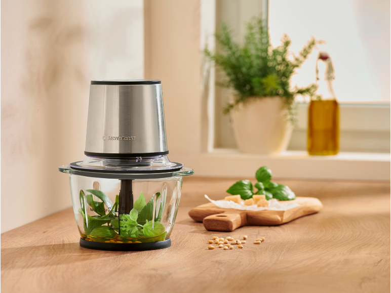 Hachoir avec basilic et huile, prêt pour la préparation du pesto.