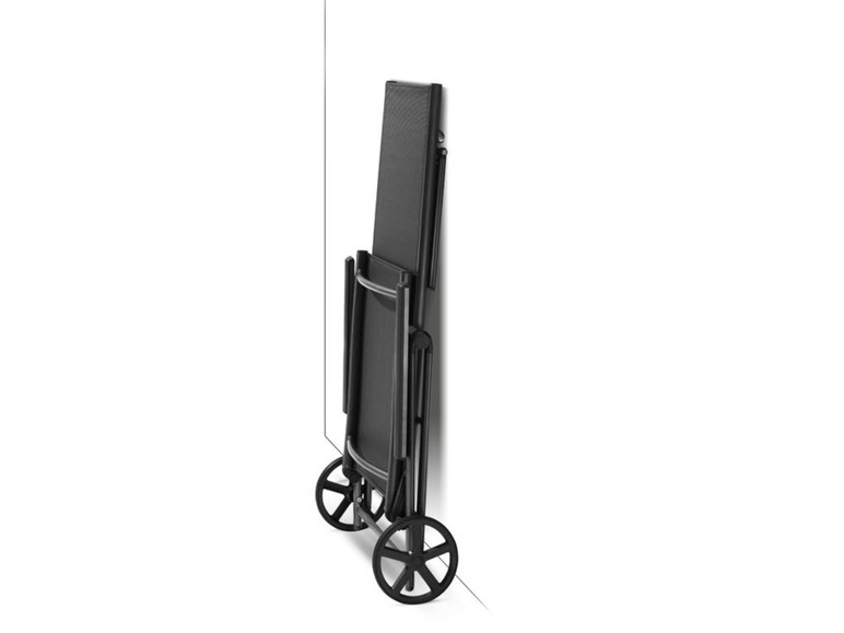 Un fauteuil inclinable noir à roulettes, replié contre un mur.