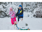 Deux enfants en vêtements d'hiver avec une luge et un petit bonhomme de neige dans un paysage enneigé.
