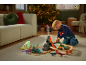 Enfant jouant avec un train et des dinosaures dans un salon de Noël.