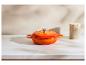 Cocotte orange sur un comptoir en marbre blanc avec un fond beige.