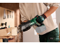 Personne avec des gants de protection utilisant une scie sabre pour couper une poutre en bois, avec de la sciure en l'air.