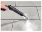 Une main utilisant un nettoyeur vapeur pour nettoyer des carreaux.