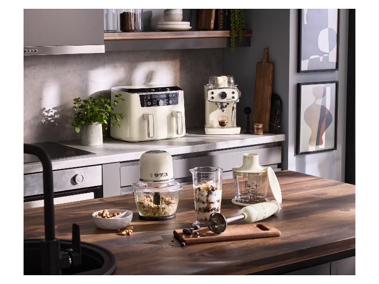 Cuisine avec friteuse à air crème, machine à expresso et mixeur sur un comptoir en bois.