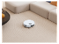 Robot aspirateur sur tapis, près d'un canapé.