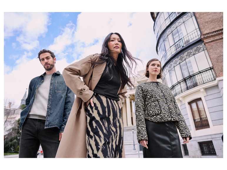 Des mannequins posent avec des vêtements élégants devant un bâtiment.