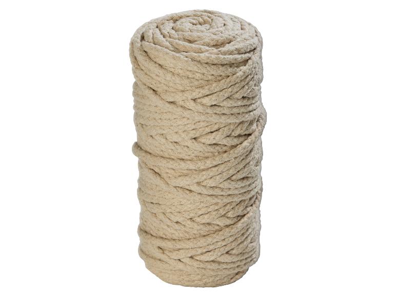 Un grand rouleau de corde beige naturelle, étroitement enroulé et debout.