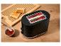Grille-pain noir avec du pain grillé, de la confiture et une planche à découper en bois.