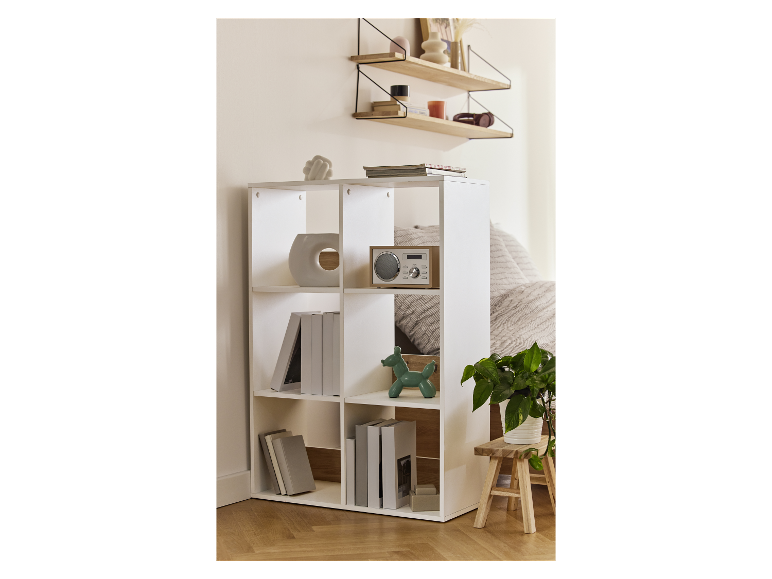 Étagère blanche à neuf cubes avec des livres, une radio et des objets décoratifs dans une chambre.