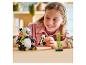 Une fille sourit en jouant avec des pandas LEGO et du bambou sur une table.