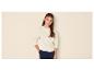 Fille en sweat-shirt beige et pantalon bleu marine, la main dans la poche.
