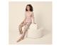 Femme en pyjama rose à motifs floraux avec l'inscription 'Stay Cozy' sur un pouf crème.