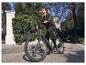 Homme roulant un vélo électrique vert sur une route pavée.