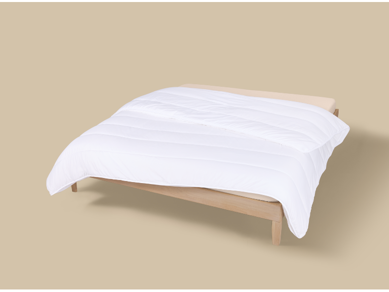 Couette blanche sur un lit en bois clair avec des draps beiges.