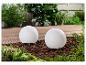 Deux lampes sphériques blanches pour extérieur, décorées dans un jardin.