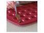 Une main verse du chocolat dans un moule en silicone rouge.