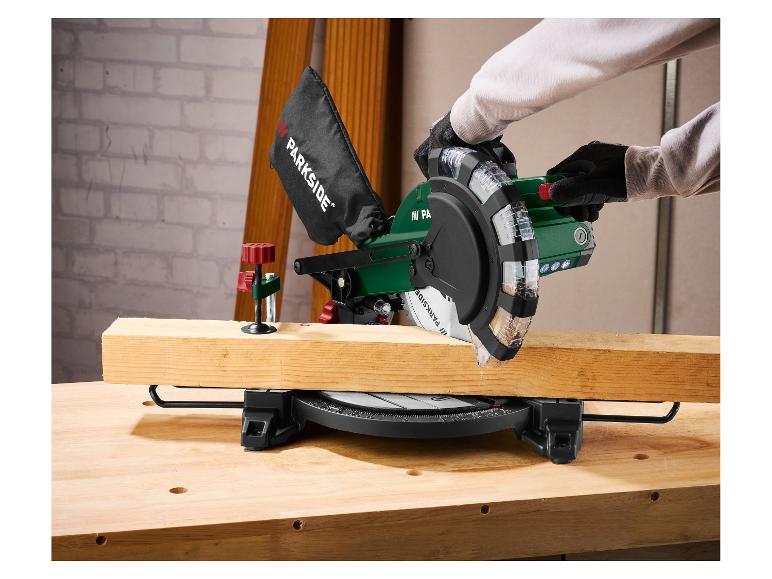 Personne coupant du bois avec une scie à onglet Parkside sur un établi.