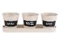 Trois pots crème avec une étiquette noire pour les herbes : menthe, basilic et sauge.