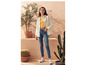 Une femme porte une chemise blanche, un jean bleu et des baskets blanches.