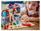 Une fille joue avec une maison et des figurines LEGO Lilo & Stitch colorées.
