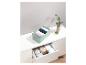 Une boîte de rangement verte avec des vêtements, sur une commode blanche avec un tiroir ouvert contenant d'autres boîtes de rangement.
