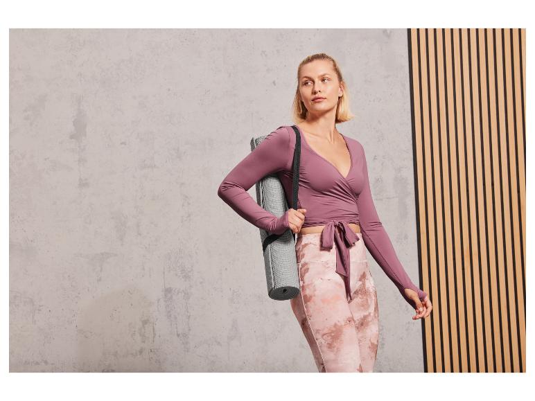 Une femme vêtue de vêtements de sport roses avec un tapis de yoga.