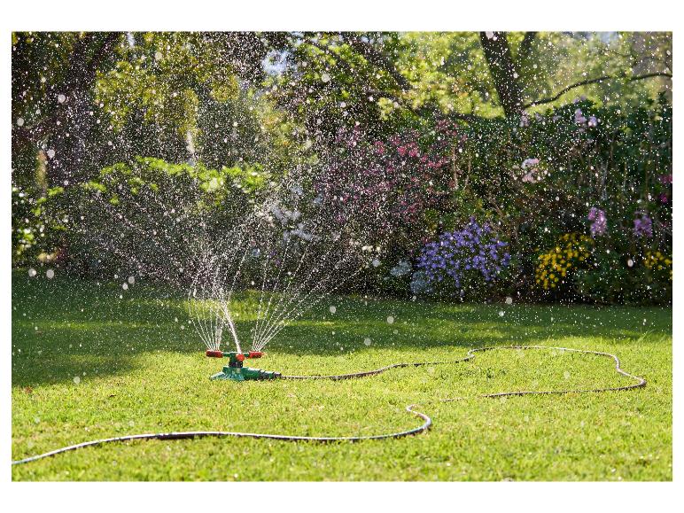 Un arroseur arrose la pelouse dans le jardin.