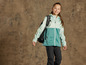 Une fille porte une veste softshell verte avec un sac à dos.