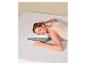 Femme dormant sur un oreiller ergonomique blanc et gris sur un lit aux draps blancs.