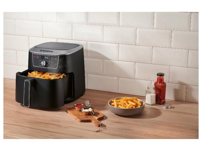 Friteuse à air avec frites, ketchup et mayonnaise sur un comptoir en bois.