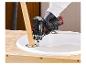 Une main tenant un tournevis Parkside pour visser une patte de table en bois.