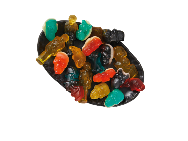 Bonbons gélifiés d'Halloween aux formes effrayantes comme des squelettes, des crânes et des chauves-souris sur une assiette noire.
