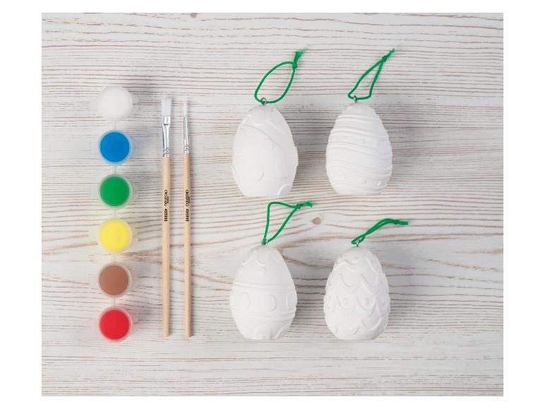 Kit de peinture d'œufs de Pâques avec œufs blancs, peintures et pinceaux sur fond en bois.