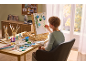 Jeune artiste peignant sur une toile à l'aide d'un coffret de peinture de table avec accessoires.